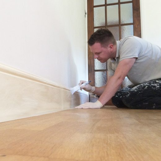 Happy Homes team member painting a skirting board